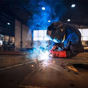 welder in safety gear working in factory setting