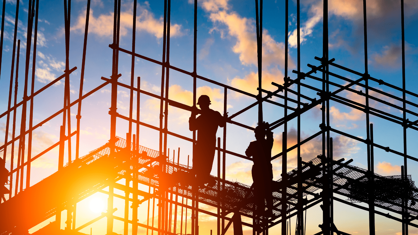 Workers assembling construction scaffolding during sunrise on building project